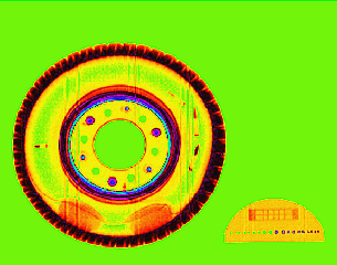 Fragment  of cargo  container  image in pseudo color. Four cartridges and two packings with narcotics are hidden inside the truck wheel. On the right side a defectometer for measurements of spatial and density resolution is placed.